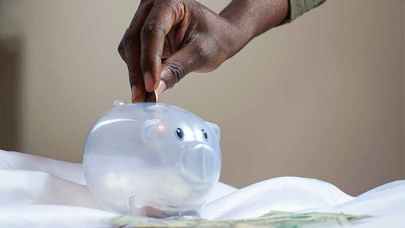 hand putting money in piggy bank